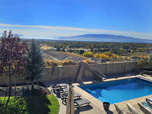 View of swimming pool featuring a fenced backyard, a fenced in pool, a water slide, and a mountain view