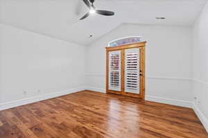 Spare room featuring visible vents, wood finished floors, baseboards, a ceiling fan, and vaulted ceiling
