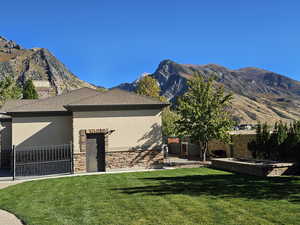 View of front of home with fence, a mountain view, stucco siding, and a front lawn