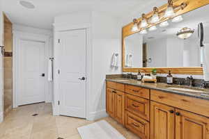 Full bathroom featuring double vanity, a sink, baseboards, and tile patterned flooring
