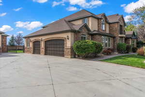 View of property exterior with a garage, fence, stone siding, stucco siding, and driveway