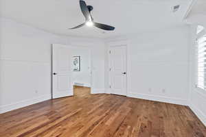 Unfurnished bedroom with visible vents, a wainscoted wall, and wood finished floors