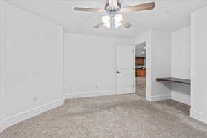Spare room featuring carpet floors, a ceiling fan, and baseboards