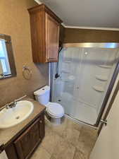 Bathroom with a textured wall, tile patterned flooring, vanity, toilet, and a stall shower