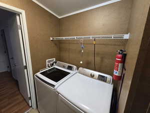 Washroom with a textured wall, laundry area, wood finished floors, and washing machine and clothes dryer
