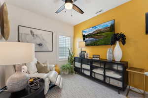 Living area featuring visible vents, carpet flooring, and a ceiling fan