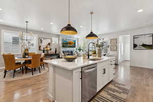 Kitchen featuring white cabinets, a sink, a fireplace, open floor plan, and stainless steel dishwasher