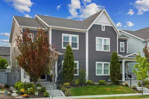 View of front of property featuring a front lawn, a shingled roof, board and batten siding, a porch, and stairway