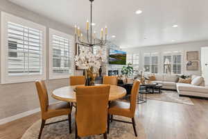 Dining area with a fireplace, a chandelier, recessed lighting, baseboards, and wood finished floors