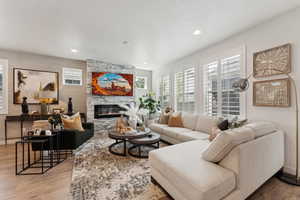 Living room with a stone fireplace, recessed lighting, and wood finished floors