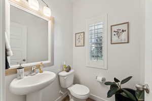 Half bath featuring baseboards, a sink, and toilet