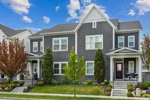 Townhome / multi-family property with board and batten siding, a porch, and a front yard