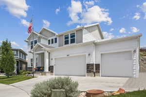 View of front of property with board and batten siding, stone siding, and concrete driveway