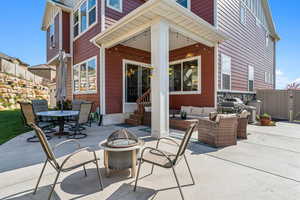 View of patio with outdoor dining area, fence, an outdoor living space with a fire pit, entry steps, and a grill
