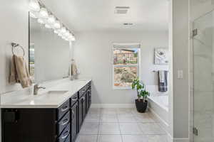 Bathroom with visible vents, tile patterned flooring, double vanity, a bath, and a sink