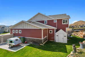 Back of house with fence, a storage unit, board and batten siding, an outbuilding, and a lawn