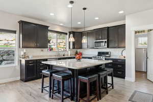 Kitchen featuring appliances with stainless steel finishes, a kitchen island, a breakfast bar, and tasteful backsplash