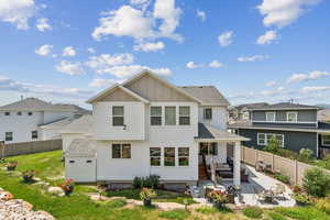 Rear view of house with a shingled roof, a patio area, board and batten siding, a fenced backyard, and an outdoor hangout area