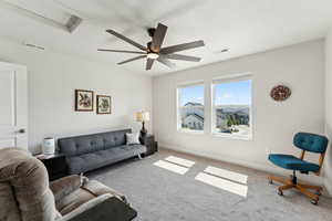 Carpeted living room with visible vents, a ceiling fan, and baseboards
