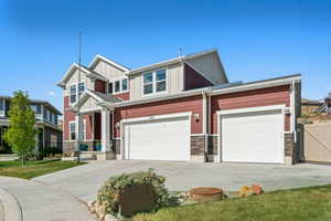 Craftsman inspired home with board and batten siding, fence, driveway, and stone siding