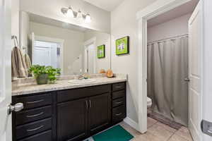Bathroom featuring vanity, tile patterned floors, toilet, and curtained shower