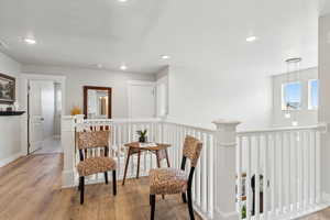 Living area with wood-type flooring, recessed lighting, visible vents, and an upstairs landing