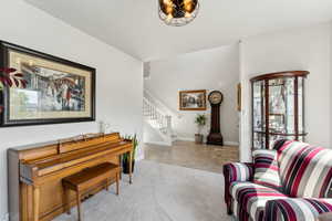 Living area featuring carpet floors, stairs, plenty of natural light, and baseboards