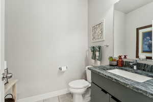 Bathroom with toilet, baseboards, tile patterned flooring, and vanity