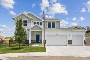 Craftsman inspired home featuring stone siding, board and batten siding, and concrete driveway