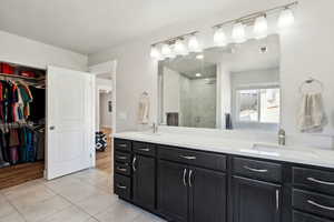 Bathroom featuring a sink, tile patterned floors, a shower stall, and double vanity