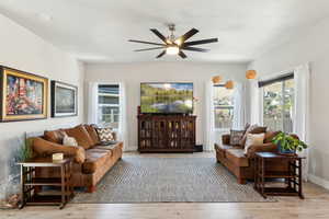 Living room featuring ceiling fan, a wealth of natural light, and wood finished floors
