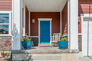Doorway to property with covered porch and stone siding