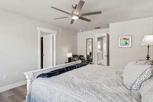 Bedroom with baseboards, ceiling fan, wood finished floors, and visible vents