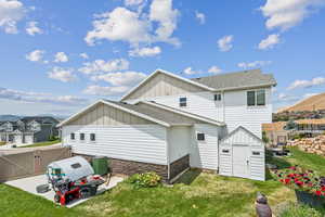Back of house with board and batten siding, stone siding, a gate, a residential view, and a shingled roof