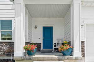 Doorway to property with covered porch and stone siding