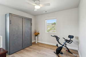 Workout room featuring light wood-type flooring, baseboards, ceiling fan, and visible vents