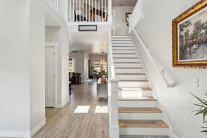 Stairs with baseboards, a high ceiling, wood finished floors, and visible vents