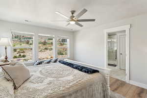 Bedroom with visible vents, ceiling fan, a textured ceiling, light wood finished floors, and ensuite bath
