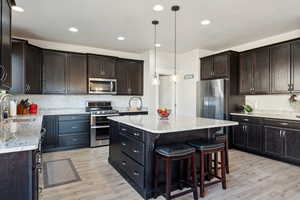 Kitchen with a sink, backsplash, stainless steel appliances, and light wood finished floors