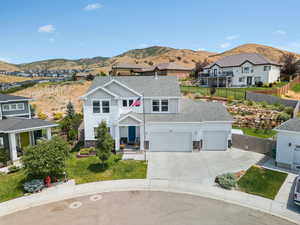 View of front of house with stone siding, a mountain view, a shingled roof, and driveway