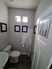 Half bath "Powder Room" just off the dining area on the main level.  featuring wide baseboards, toilet, pedestal sink, and LVP floors