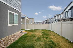 View of side yard featuring a residential view and a fully fenced backyard with automatic sprinklers.