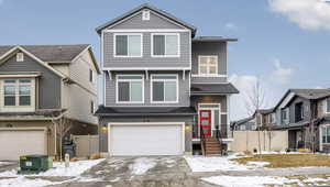 View of front of property featuring fence, driveway, and a garage