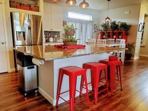 Modern kitchen featuring a healthy amount of sunlight, walk-in pantry, large island with seating for eight+, stainless steel appliances, white shaker cabinetry, undermount black granite kitchen sink, beautiful hexagon backsplash, recessed lighting, custom