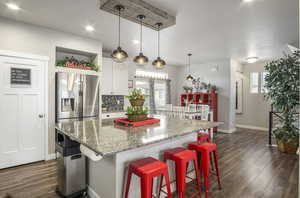Modern kitchen featuring a healthy amount of sunlight, walk-in pantry, large island with seating for eight+, stainless steel appliances, white shaker cabinetry, undermount black granite kitchen sink, beautiful hexagon backsplash, recessed lighting, custom