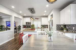 Comfortable dining area featuring LVP floors, balcony access, stairway to third level with metal handrails