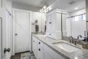 Full primary ensuite featuring a subway tile stamped insert double vanity with undermount sinks, wide baseboards and vinyl flooring