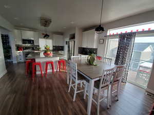 Modern kitchen featuring a healthy amount of sunlight, walk-in pantry, large island with seating for eight+, stainless steel appliances, white shaker cabinetry, undermount black granite kitchen sink, beautiful hexagon backsplash, recessed lighting, custom