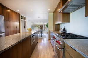 Kitchen with modern cabinets, recessed lighting, ventilation hood, light wood-style flooring, and appliances with stainless steel finishes