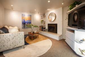 Living area with carpet flooring, recessed lighting, and a brick fireplace